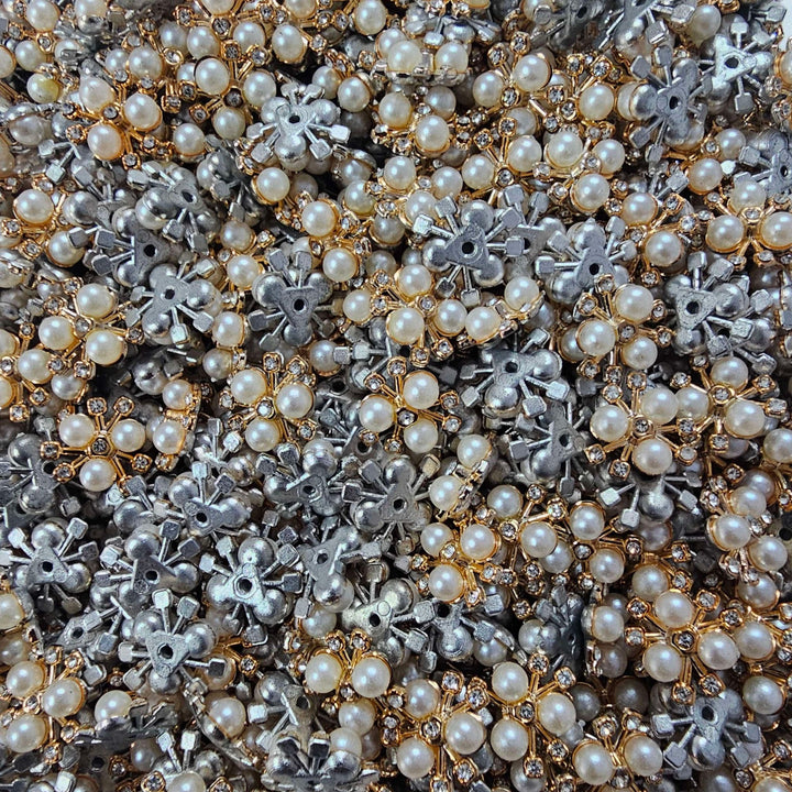 Close-up of a pile of pearl and metal embellishments in gold, silver, and bronze.
